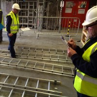 Medewerkers met veiligheidshelmen bij liggende steigeronderdelen